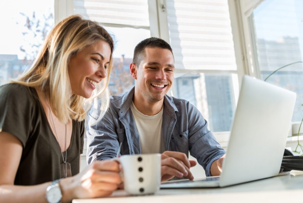 Smiling young couple looking at laptop